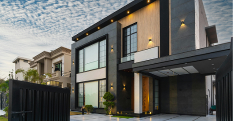 Maison moderne avec façade noire et bois, grandes fenêtres et toit plat.