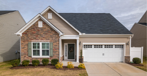 Maison de plain-pied avec façade en briques, garage et jardin soigné.